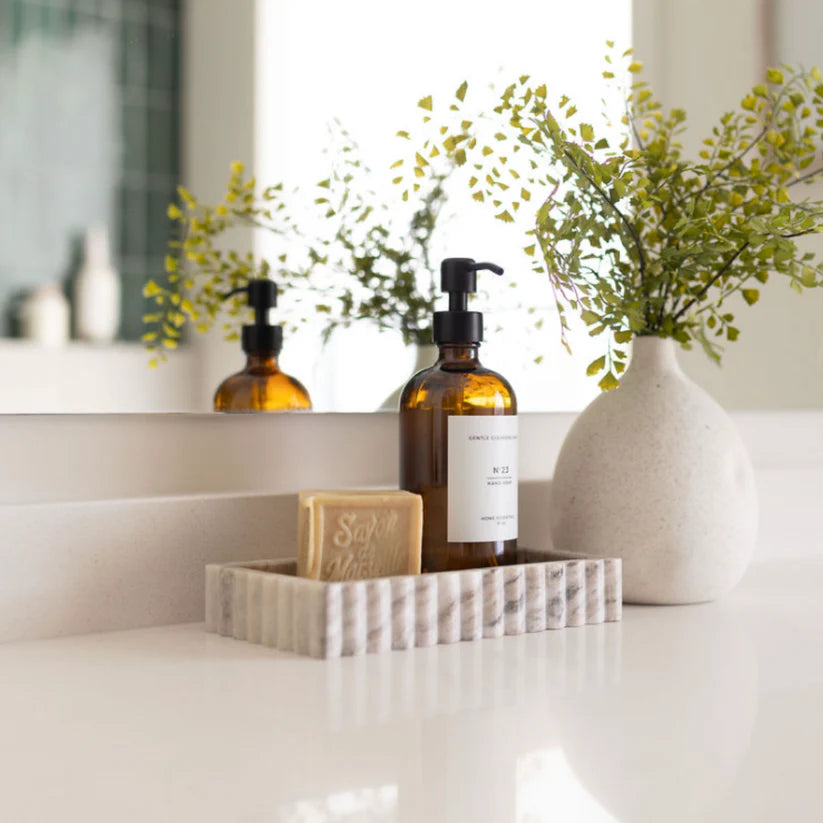 Bathroom counter with bottles, soap, and a vase with plants